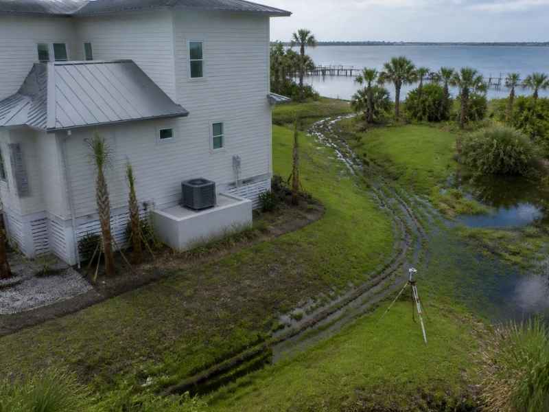 Coastal home in Pensacola Florida with elevated outdoor HVAC equipment and survey equipment documenting property elevation conditions after flood protection improvements