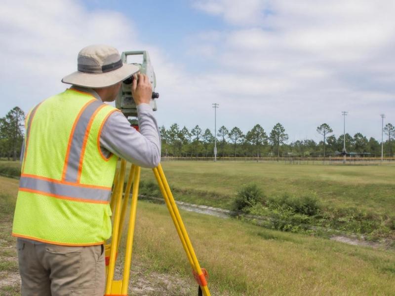Land surveyor collecting topographic data for a community sports complex site in Pensacola, Florida.